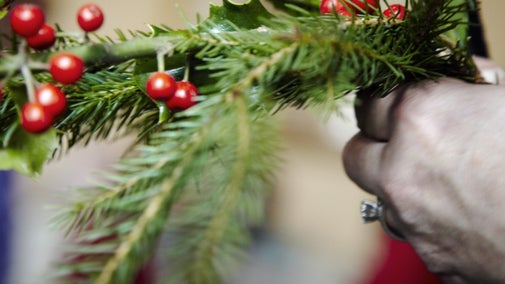 Image shows Christmas foliage being arranged during a wreath making course